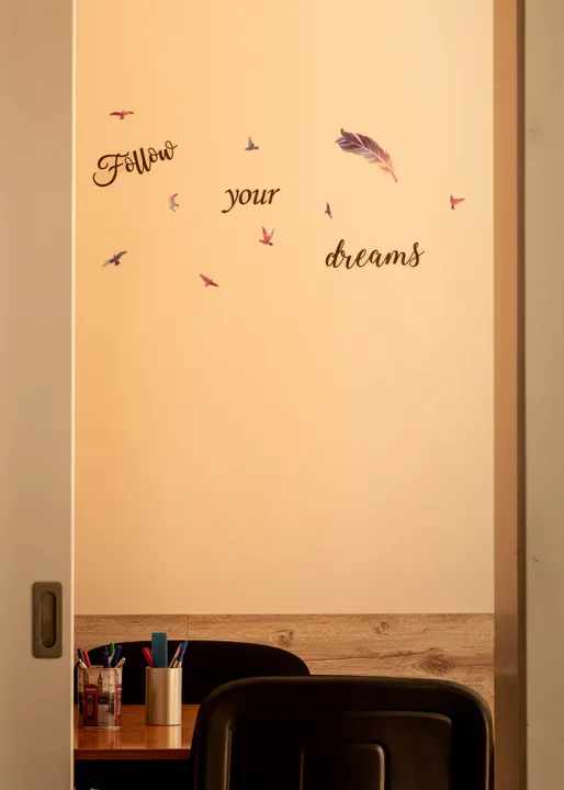 Надпис „Follow your dreams“ на стената до учебна маса
